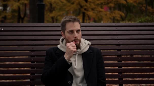 一个男人坐在长椅上 在公园里抽一支电子香烟 — 图库视频影像