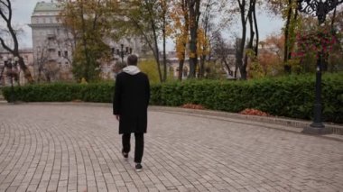 Bir adam parkta yürüyor, arkadan bakıyor.