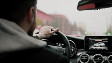 Şehirde pahalı lüks bir araba kullanan çekici bir adam.