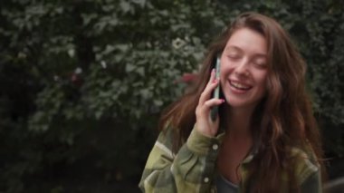 Şehirde yürürken telefonda konuşan güzel, çekici bir genç kız.