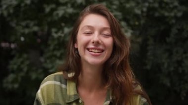 Güzel, çekici, genç bir kadın saçını düzelten kameraya bakıyor.