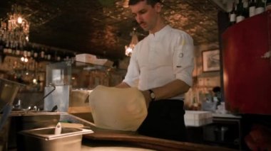 Şef restoran içinde pizza hazırlıyor, açık mutfak.