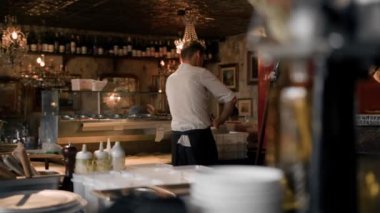 Şef restoran içinde pizza hazırlıyor, açık mutfak.