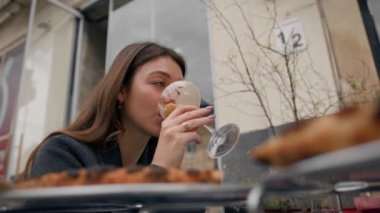 Bir kız restoranın terasında tek başına oturur ve kokteyl içer.