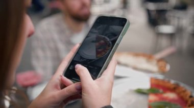 Bir kadın, bir kızla randevusu sırasında telefonunda pizza yerken fotoğrafını çeker.