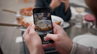 Bir adam, bir kızla randevusu sırasında telefonuyla pizza yerken fotoğrafını çekiyor.