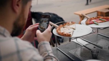 Bir adam, bir kızla randevusu sırasında telefonuyla pizza yerken fotoğrafını çekiyor.