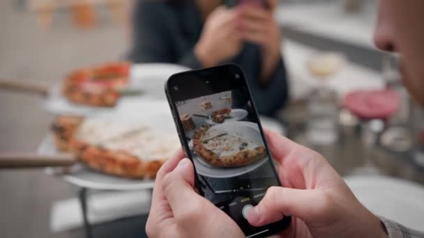 男は女の子とデート中に携帯電話でピザを食べる写真を撮る — ストック動画
