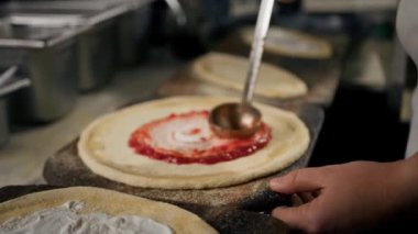 Profesyonel şef geleneksel margarita pizza yapar. Pizza üzerine domates ezmesi ve peynir ekle.