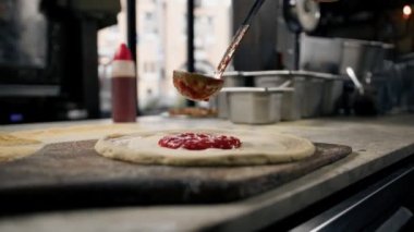 Profesyonel şef geleneksel margarita pizza yapar. Pizza üzerine domates ezmesi ve peynir ekle.
