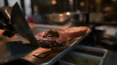Hamburger pişirme süreci, aşçı restoran mutfağında çöreğe malzeme ekliyor.