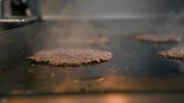 Restoranın mutfağındaki şef hamburgerler için pirzola yapar. Biftek ezer.