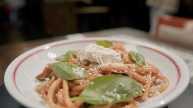 Yakın plan - restoranda dönen bir masada makarna, arka planda bulanık bir şekilde çalışan bir restoran.