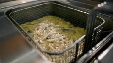 Yakın çekim. Profesyonel bir restoranın mutfağında patates kızartması pişirme işlemi.