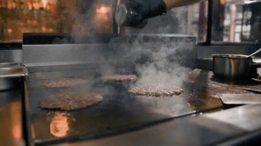 Restoranın mutfağındaki şef hamburgerler için pirzola yapar. Biftek ezer.