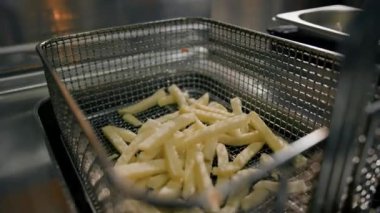 Yakın çekim. Profesyonel bir restoranın mutfağında patates kızartması pişirme işlemi.