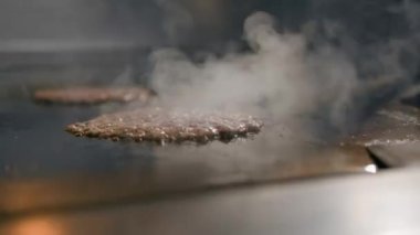 Restoranın mutfağındaki şef hamburgerler için pirzola yapar. Biftek ezer.