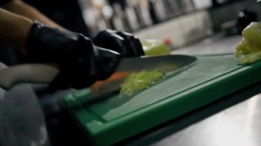 Aşçı profesyonel mutfakta bir restoranda sebze (lahana) keser.