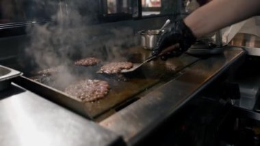 Restoranın mutfağındaki şef hamburgerler için pirzola yapar. Biftek ezer.