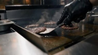Restoranın mutfağındaki şef hamburgerler için pirzola yapar. Biftek ezer.
