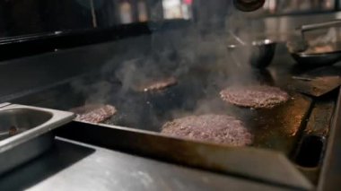 Restoranın mutfağındaki şef hamburgerler için pirzola yapar. Biftek ezer.