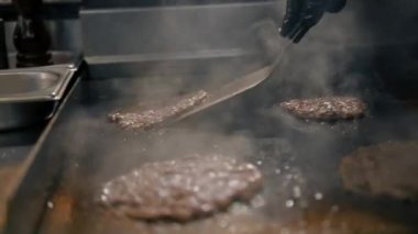 Restoranın mutfağındaki şef hamburgerler için pirzola yapar. Biftek ezer.