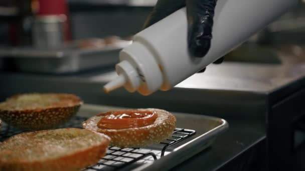 バーガーの調理法 レストランのキッチンでパンにソースを追加シェフ — ストック動画