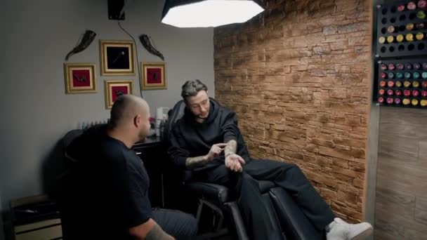 Εσωτερικό Ενός Στούντιο Τατουάζ Άνθρωπος Δείχνει Τατουάζ Του Έναν Καλλιτέχνη — Αρχείο Βίντεο