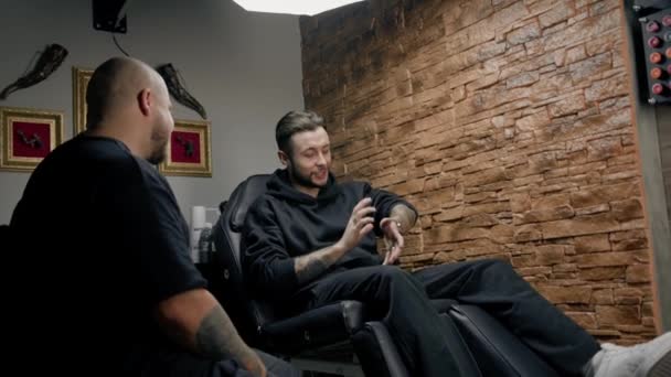 Dövme Stüdyosunun Içinde Bir Adam Dövmelerini Usta Bir Dövmeciye Gösteriyor — Stok video