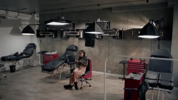 Weitwinkelaufnahme Tätowiererin Sitzt Auf Einem Stuhl Und Wartet Auf Einen — Stockvideo