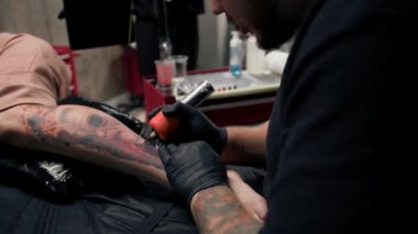 Yakın plan, bir kadının bacağına dövme yapma süreci. Erkek dövme sanatçısı dövme yapıyor.