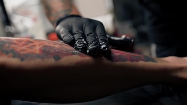 男性タトゥーアーティストは 迅速な治癒のためのセッションの後にタトゥーに軟膏を笑顔 タトゥースタジオ — ストック動画