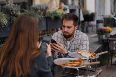 Restoranda oturmak, akıllı telefonlardan mesaj atmak. Erkek arkadaş, kız arkadaş buluşmada cep telefonuna bakıyor.