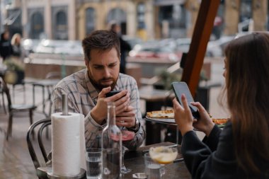 Restoranda oturmak, akıllı telefonlardan mesaj atmak. Erkek arkadaş, kız arkadaş buluşmada cep telefonuna bakıyor.