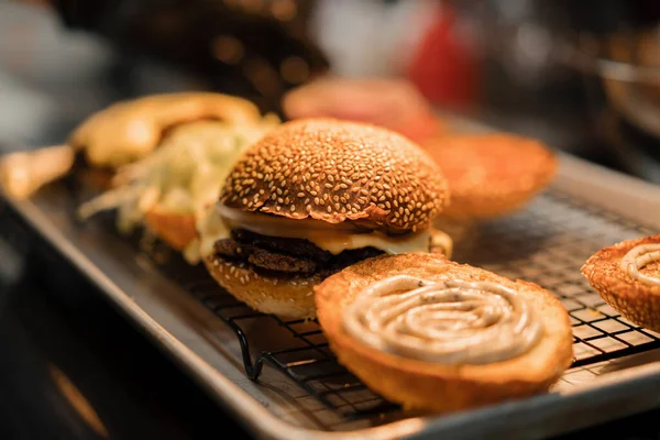 Burger cooking process , chef adding ingredients to bun in restaurant kitchen