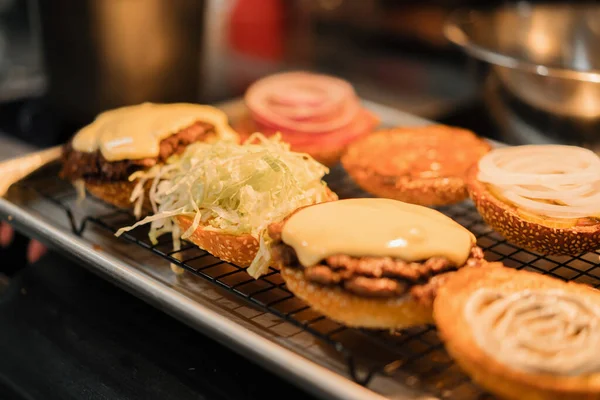 Burger cooking process , chef adding ingredients to bun in restaurant kitchen