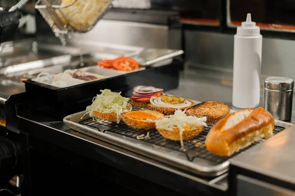 Процесс Приготовления Гамбургеров Повар Добавляет Ингредиенты Булочку Кухне Ресторана — стоковое фото