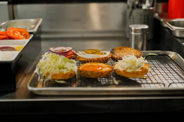 Процесс Приготовления Гамбургеров Повар Добавляет Ингредиенты Булочку Кухне Ресторана — стоковое фото
