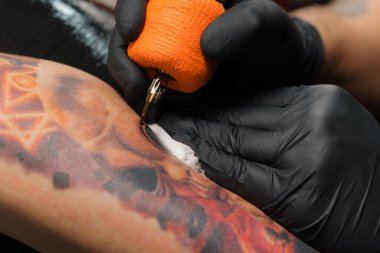 Yakın plan, bir kadının bacağına dövme yapma süreci. Erkek dövme sanatçısı dövme yapıyor.