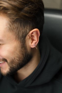 Dövme delme stüdyosu. Kadın bir erkeğe kulak delici yapar.