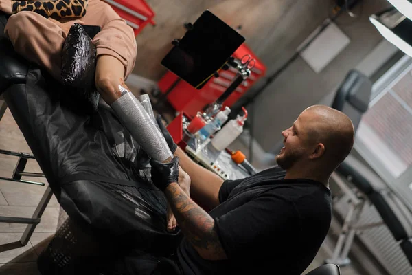 Artista Del Tatuaje Masculino Tira Tatuaje Con Una Película Cliente — Foto de Stock
