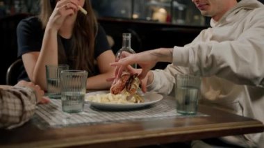 Yakın plan. Bir adam, arkadaşlarıyla birlikte hamburger ve patates kızartması yiyor.