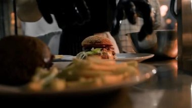 Yakın plan - profesyonel bir restoranın mutfağında patates kızartmalı hamburger hazırlama işlemi