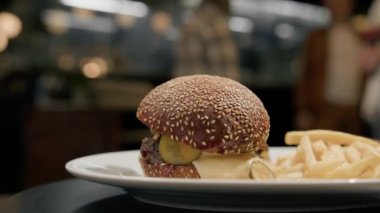 Yakın plan. Patates kızartmalı burger. Bir restoranda dönen bir masada.