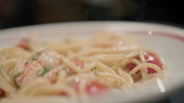 Yakın plan karides makarnası. Bir restoranda dönen masanın üzerinde. Arka planda bulanık bir şekilde çalışan bir restoran.