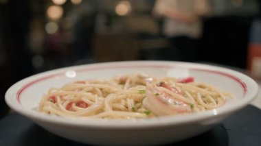 Yakın plan karides makarnası. Bir restoranda dönen masanın üzerinde. Arka planda bulanık bir şekilde çalışan bir restoran.