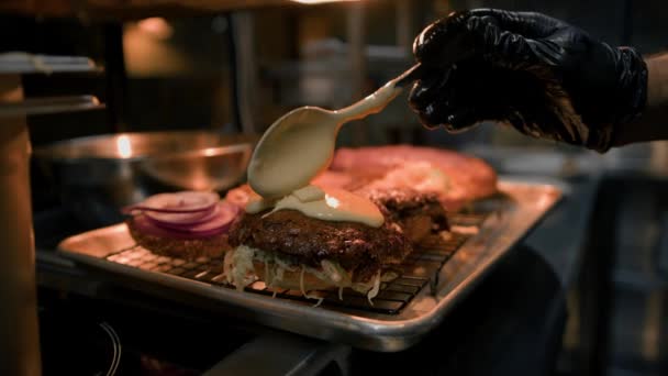 バーガーの調理法 レストランキッチンでパンに具材を加えるシェフ — ストック動画