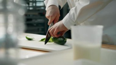 Profesyonel mutfak: şef hamburger veya salata hazırlamak için salatalık kesiyor