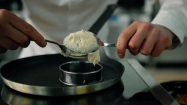 Profesyonel mutfak. Mangırı tavaya koyma süreci. Şefin yakınında tavada krep kızartılıyor..