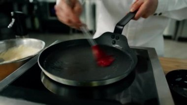 Profesyonel mutfak: Aşçı, profesyonel sobanın tepsisine yağ sürüyor..